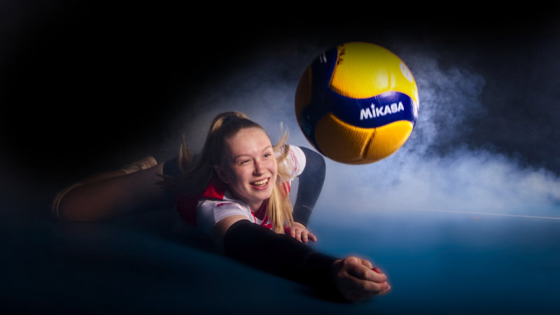 Volleyball Spielerin baggert einen Ball, im Hintergrund ist Nebel zu sehen.